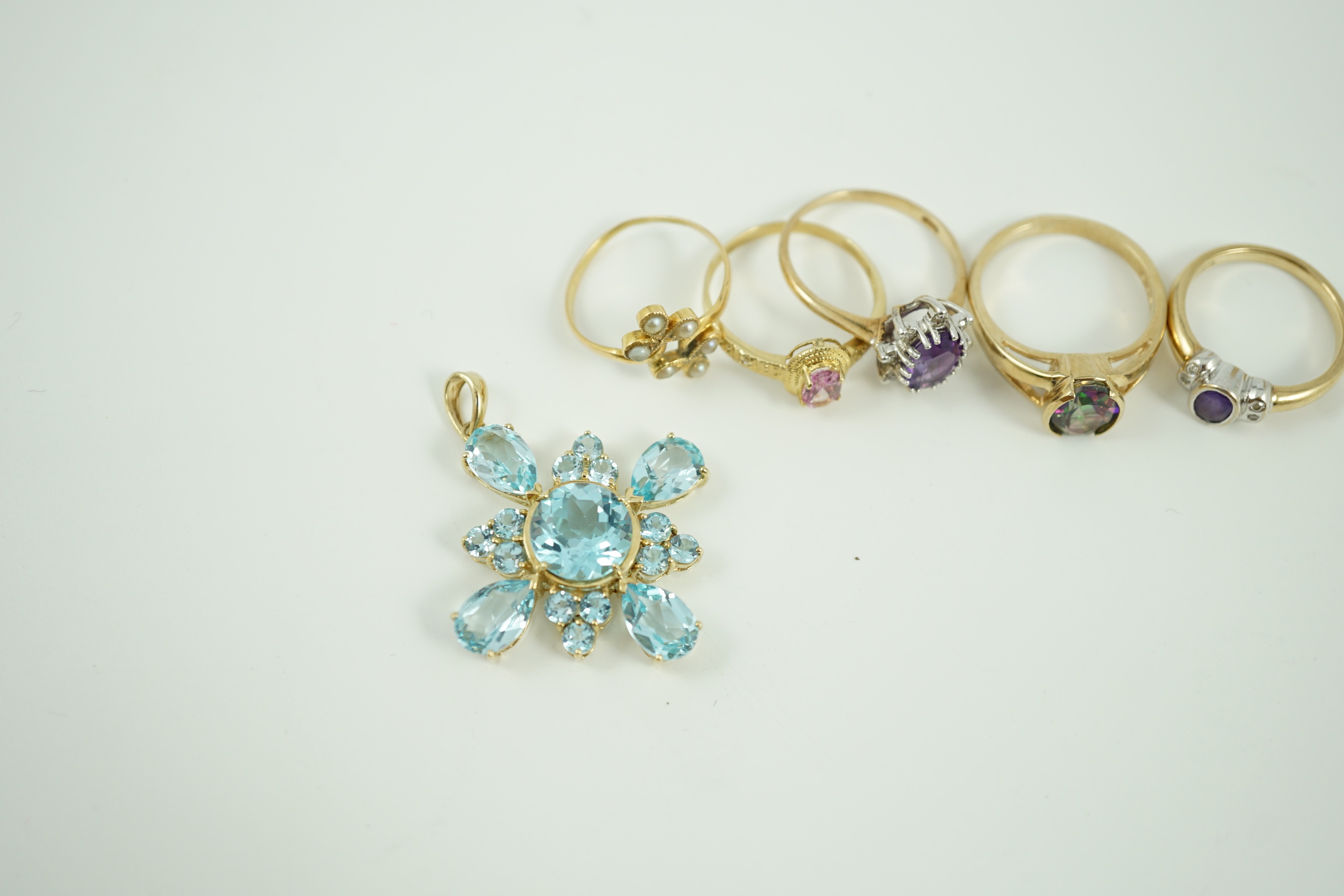 Four assorted modern 9ct gold and gem set rings, a white metal and seed pearl ring and a 9ct gold and blue stone cluster set pendant, 33mm, gross weight 17.9 grams.